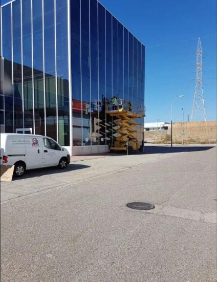 Operarios limpiando la fachada de cristal de un edificio con plataforma elevadora